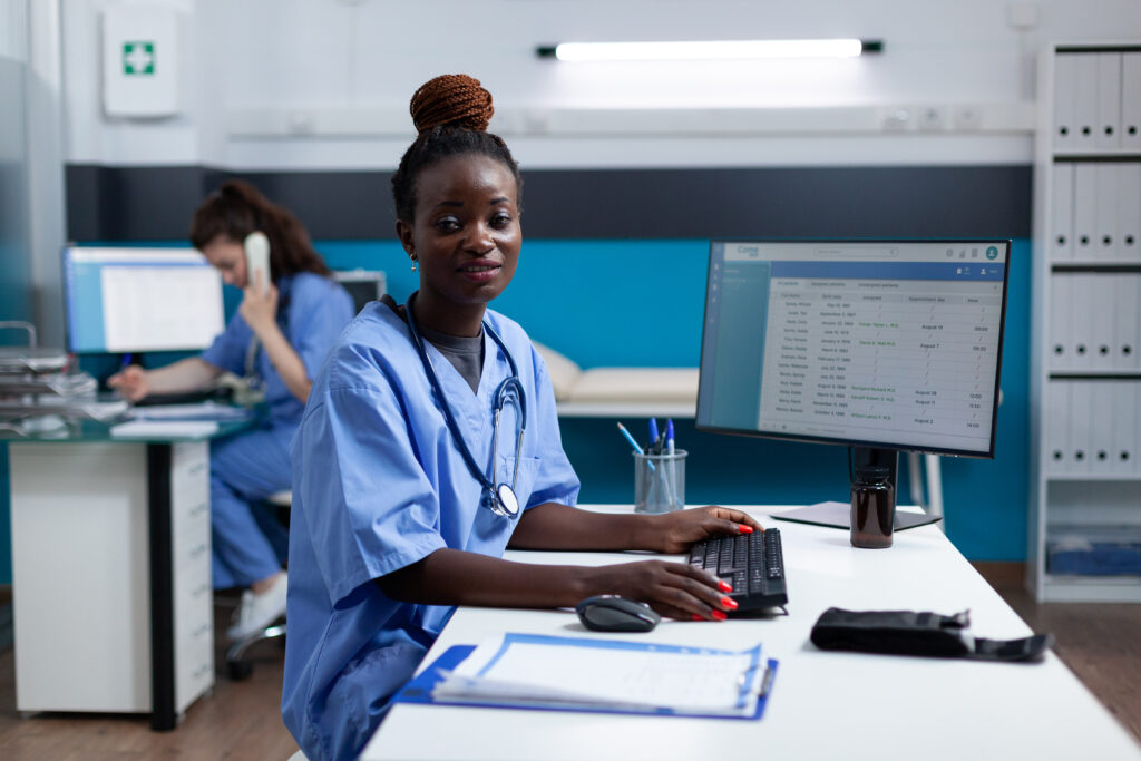 nurse in scrubs sitting at a desk
